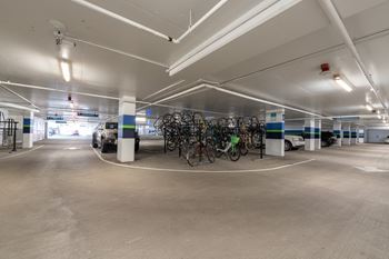 the interior of a parking garage with bicycles and cars